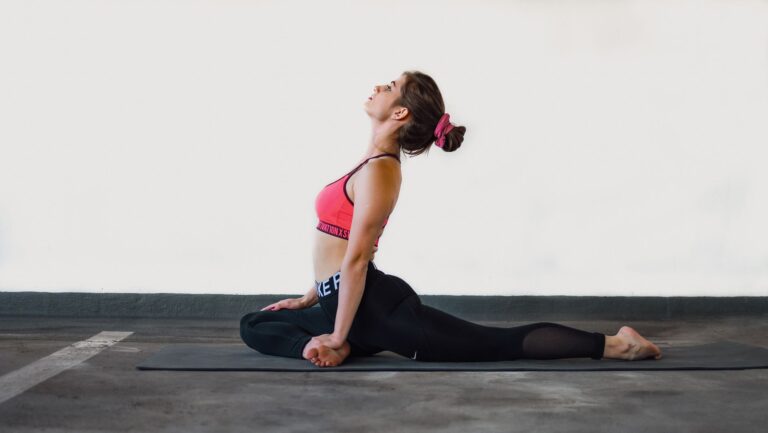 Young woman in yoga pose on mat indoors showcasing flexibility and focus.