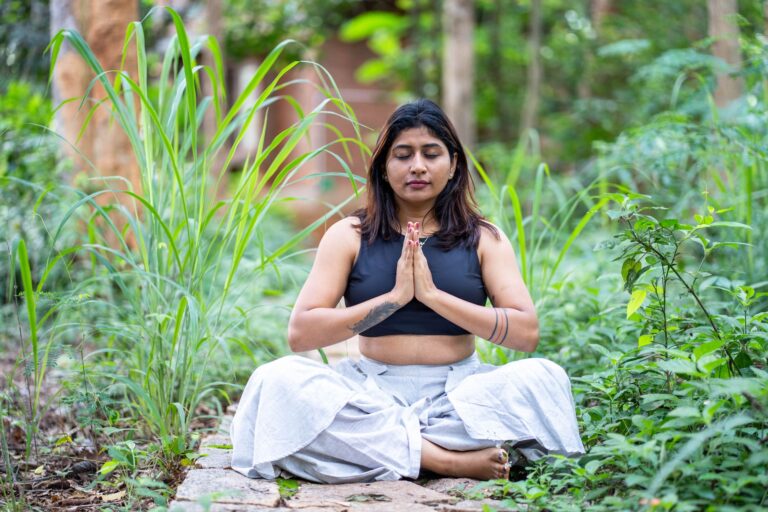 Woman meditating in lush garden setting, finding inner peace.