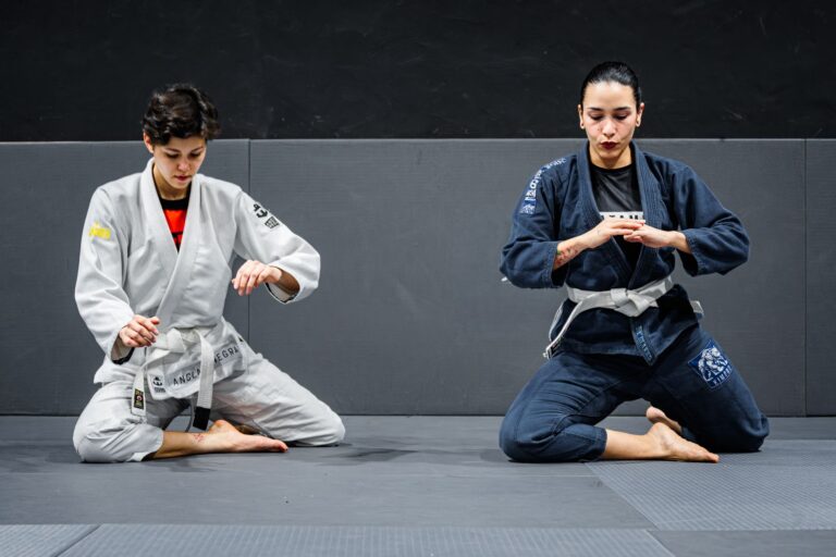 Two martial artists in gis engage in focused training in a dojo setting.