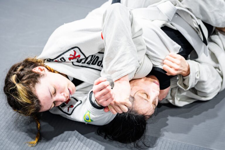 Close-up of two women practicing Brazilian Jiu-Jitsu, demonstrating intense grappling techniques.